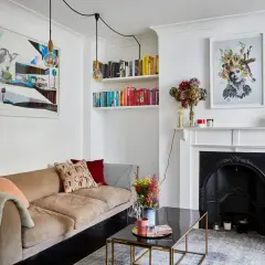 En mysig soffa med kuddar, bokhyllor fyllda med böcker och konstverk skapar en inbjudande, eklektisk inredning.