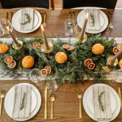 Juldukning inspiration med granris, apelsiner med nejlikor, torkade apelsinskivor och ljus. En vacker och doftande bordsdekoration.