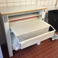 Stor mangel med ett vitt lakan som rullas ut. En stor svart soptunna står bredvid.