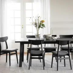 Svart matbord med sex stolar, en vas med blommor och en skål. Perfekt inspiration dekoration matbord för ett modernt hem.