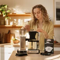 En kvinna förbereder kaffe med en Moccamaster. Hon ser till att dosera kaffet rätt för bästa smak.