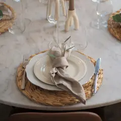 En modern juldukning med linneservetter, vita tallrikar och glas på en marmorbord.