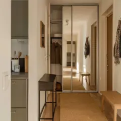 En mysig hall med en smal konsol, en bänk och en stor spegelgarderob. En matta i jute ger värme.