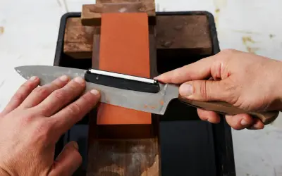Händer slipar en kniv mot en orange sten. En skärpa som gör matlagningen enklare.
