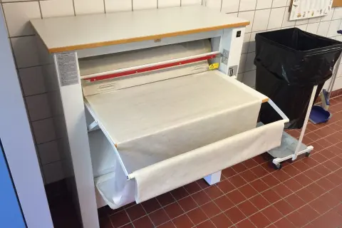 Stor mangel med ett vitt lakan som rullas ut. En stor svart soptunna står bredvid.