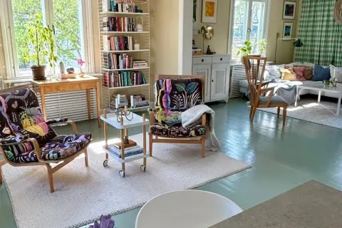 Ljust och luftigt vardagsrum med två färgstarka fåtöljer, bokhyllor och en soffgrupp. En harmonisk känsla som påminner om feng shui vardagsrum.