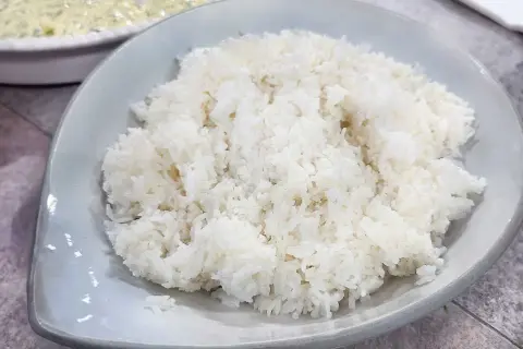 Perfekt kokt ris, enkelt att laga mat i riskokare. En skål med fluffigt vitt ris som är redo att serveras.