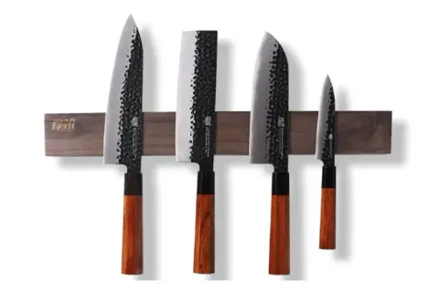 Fyra japanska knivar med hamrad yta och trähandtag, monterade på en magnetisk trälist. En samling som representerar den bästa japanska kniven för ditt kök.
