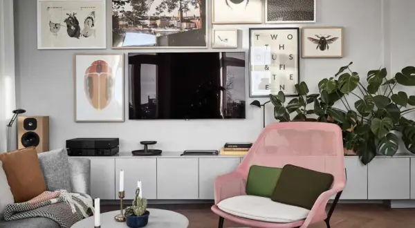En modern inredning där man valt att placera tv:n centrerat på väggen, omgiven av konst med insekter och en stadsvy.