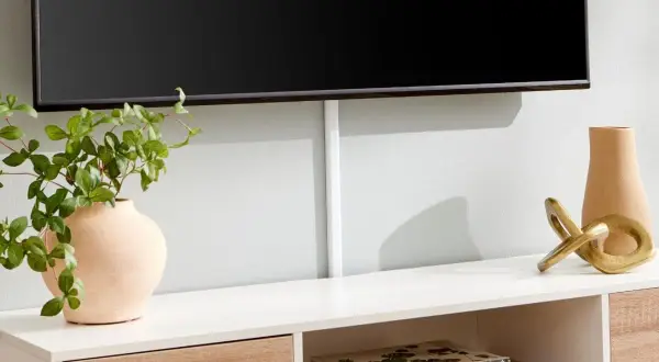 Snygg inredning tv-möbel med en vas, en guldig skulptur och böcker. Kabellisten ger ett rent intryck.