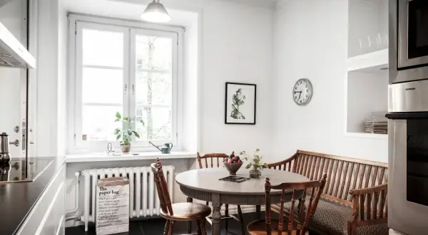 Mysig köksvrå med runt matbord, träbänk och stolar. Perfekt för runt matbord inspiration.