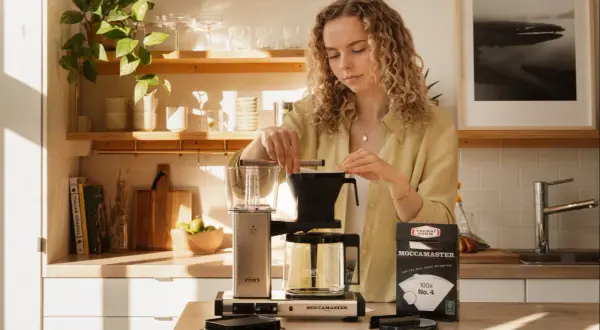 En kvinna förbereder kaffe med en Moccamaster. Hon ser till att dosera kaffet rätt för bästa smak.