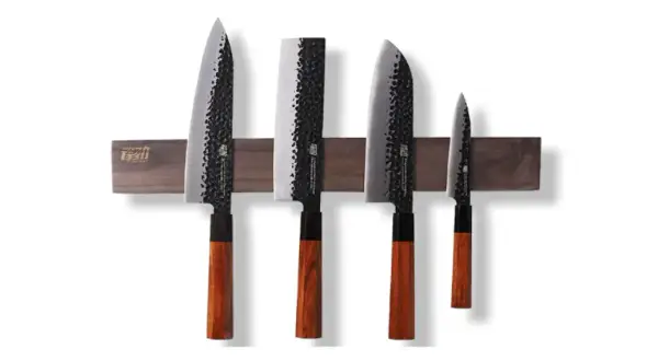 Fyra japanska knivar med hamrad yta och trähandtag, monterade på en magnetisk trälist. En samling som representerar den bästa japanska kniven för ditt kök.