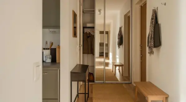 En mysig hall med en smal konsol, en bänk och en stor spegelgarderob. En matta i jute ger värme.