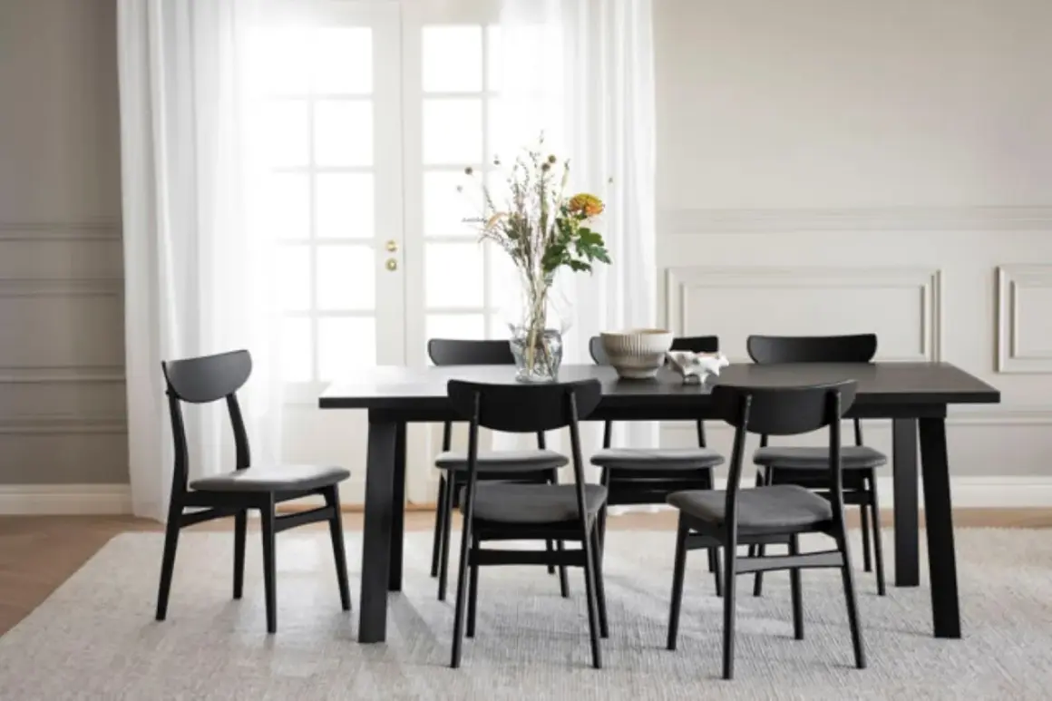 Svart matbord med sex stolar, en vas med blommor och en skål. Perfekt inspiration dekoration matbord för ett modernt hem.