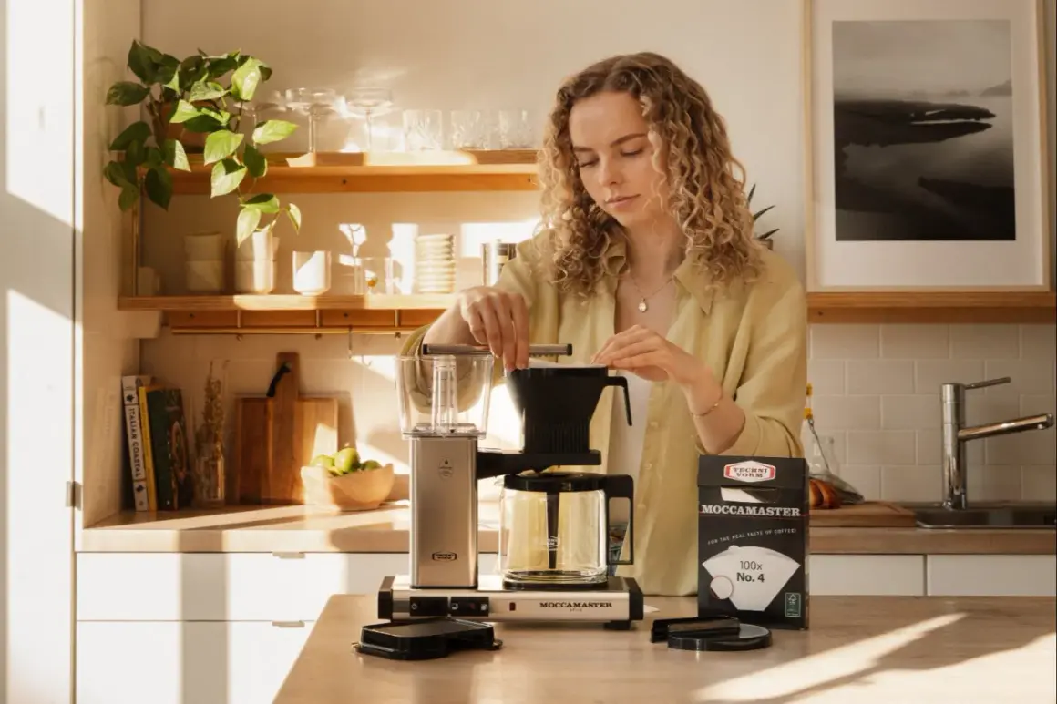 En kvinna förbereder kaffe med en Moccamaster. Hon ser till att dosera kaffet rätt för bästa smak.