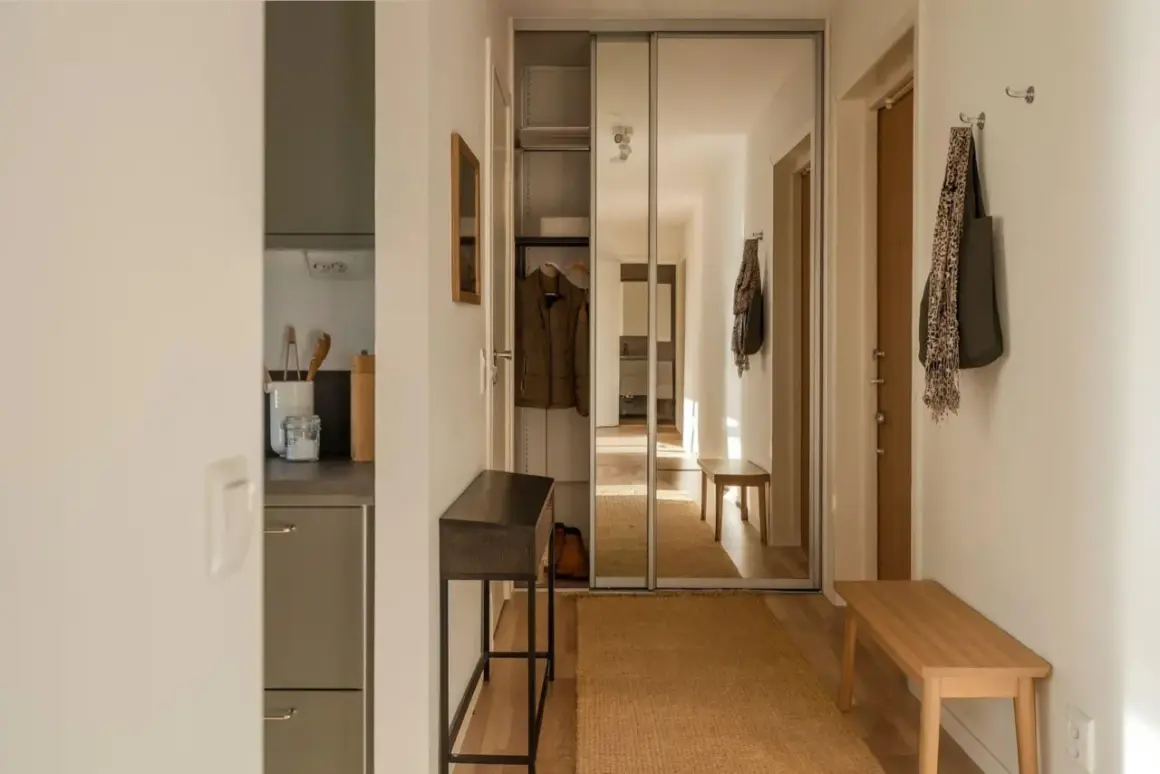 En mysig hall med en smal konsol, en bänk och en stor spegelgarderob. En matta i jute ger värme.