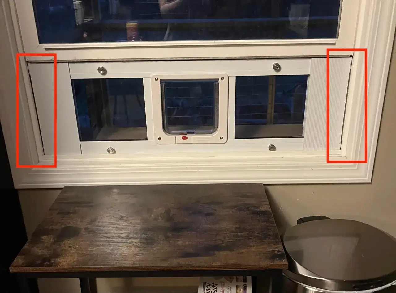 Fönster med en isolerad kattlucka installerad. Den vita ramen runt luckan ger en ren look.
