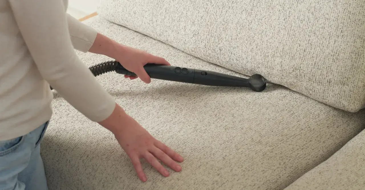 Person använder ångtvätt för att få bort kisslukt från soffa.